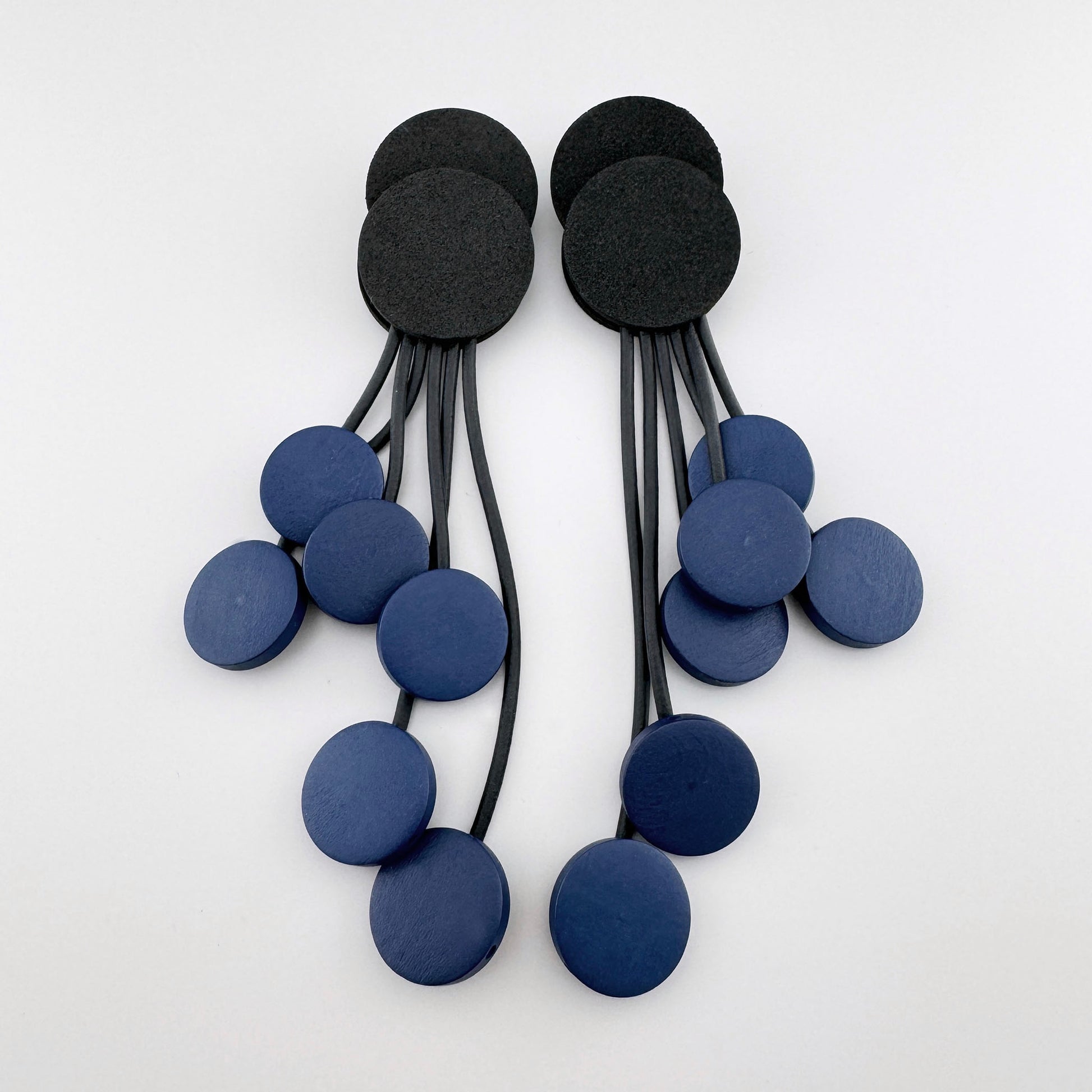 Long earrings with black and blue round elements on dangling strings.