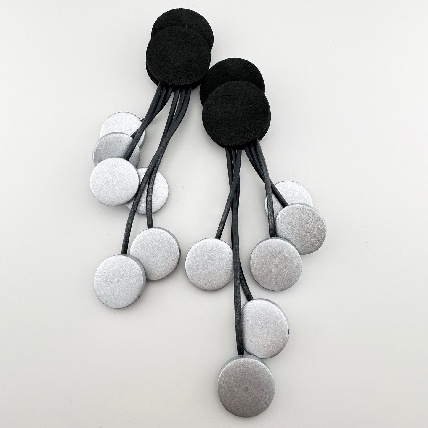 Handmade long earrings with a unique mix of silver and black circles, crafted from wood and rubber by Spanish brand Sonata.