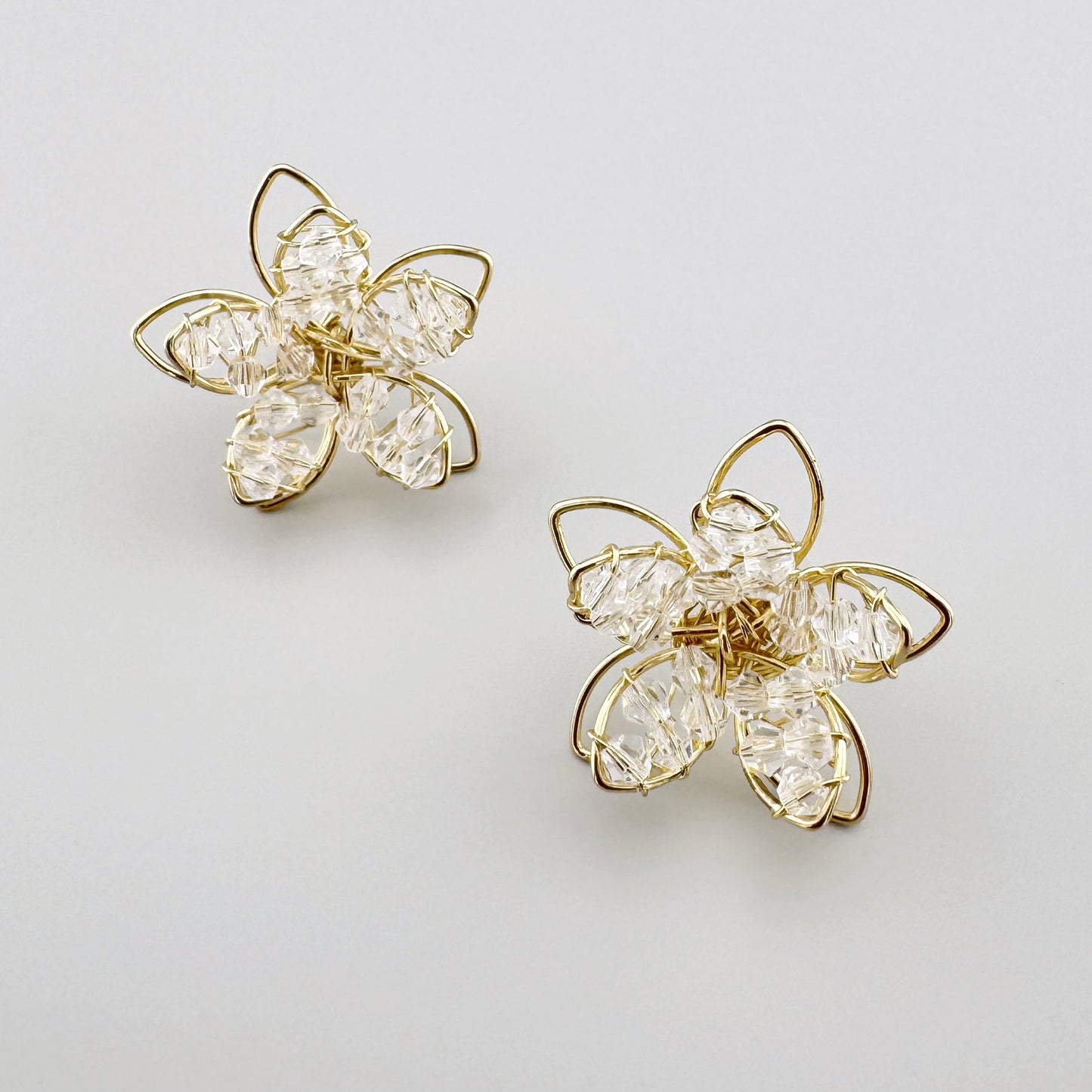 Gold flower-shaped earrings with clear crystals and delicate detailing.