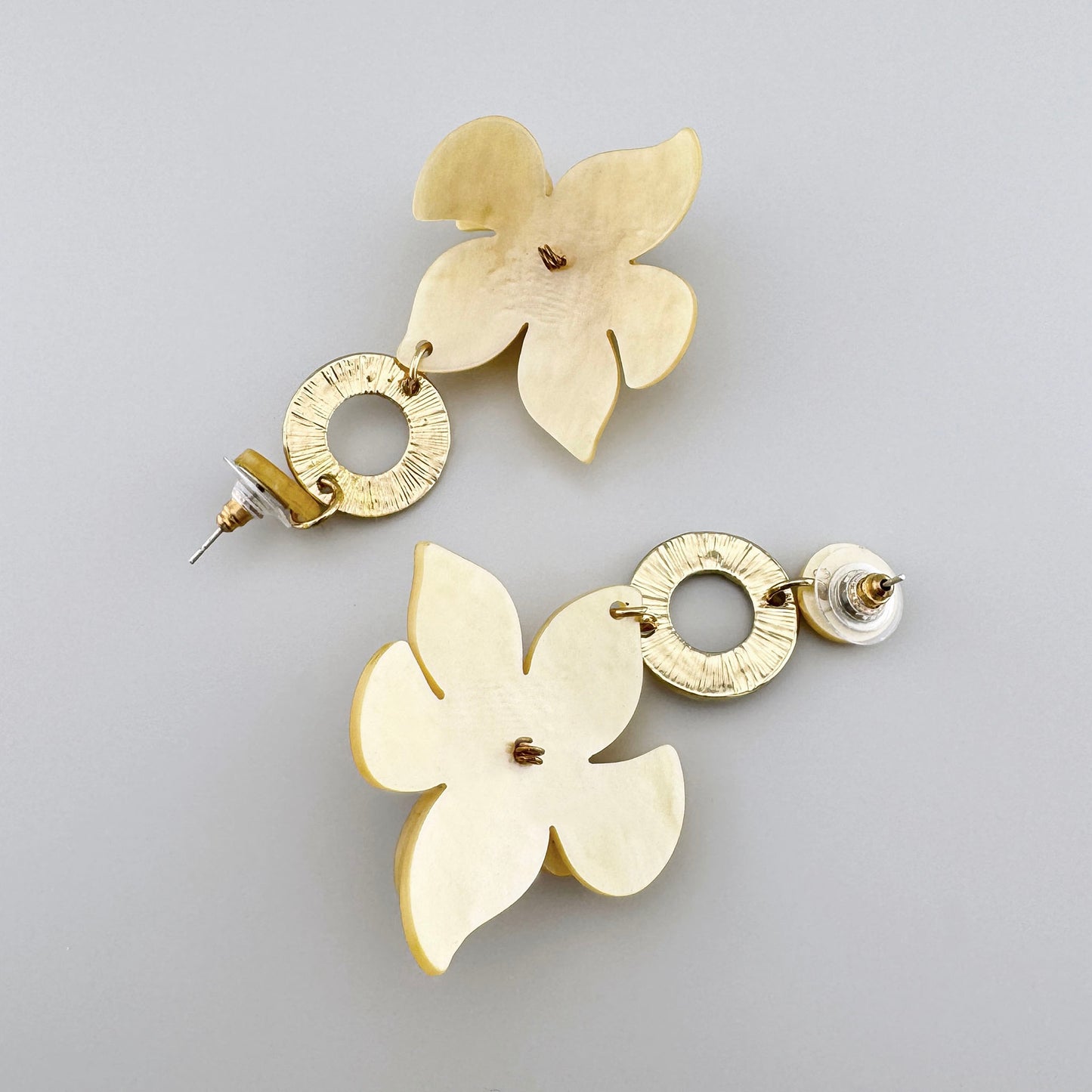 Golden flower-shaped earrings adorned with red gemstones and textured metal accents.