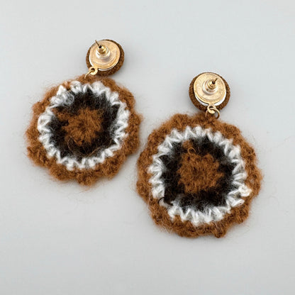 Handmade crochet earrings in brown and white tones.