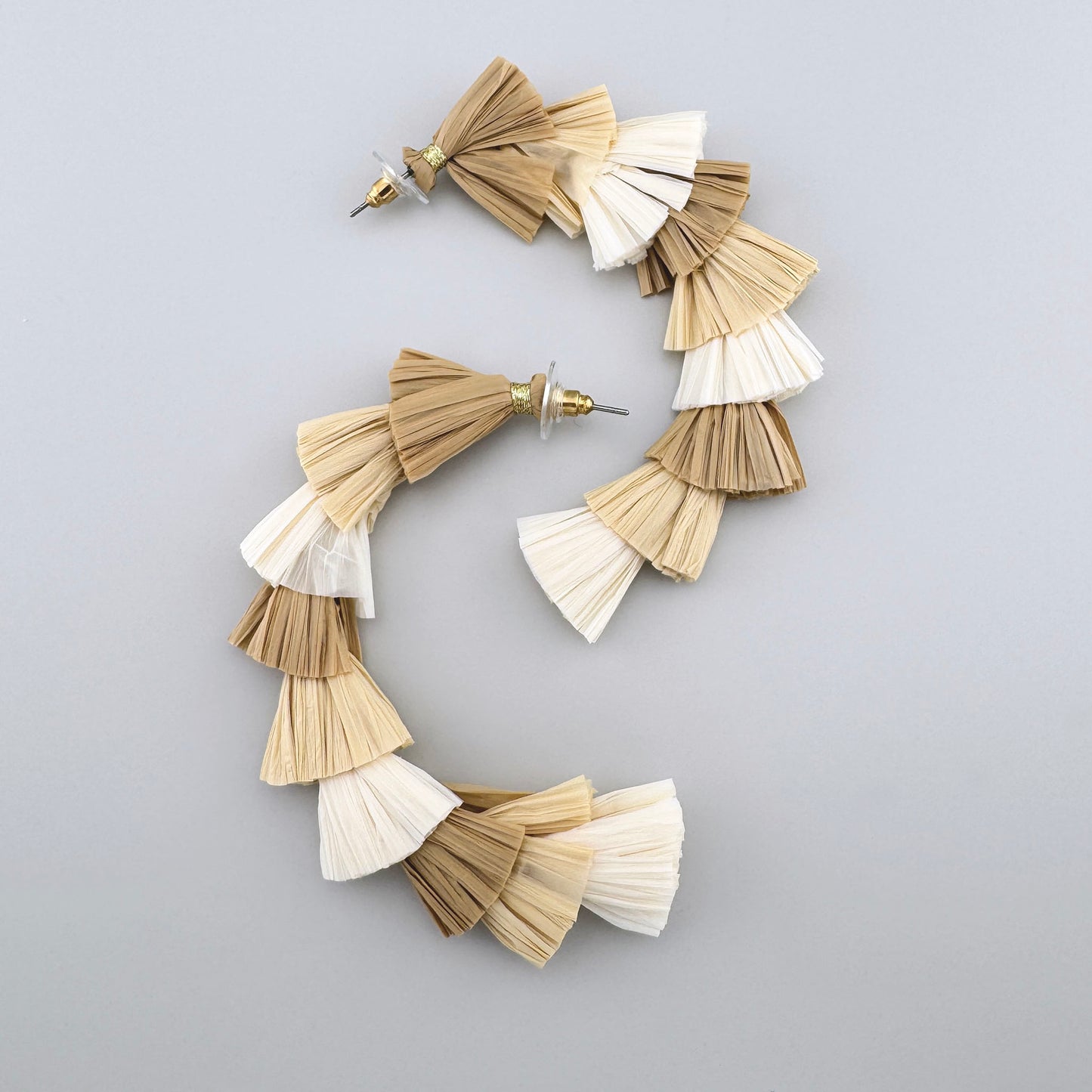 Layered tassel earrings made from natural materials in beige tones.