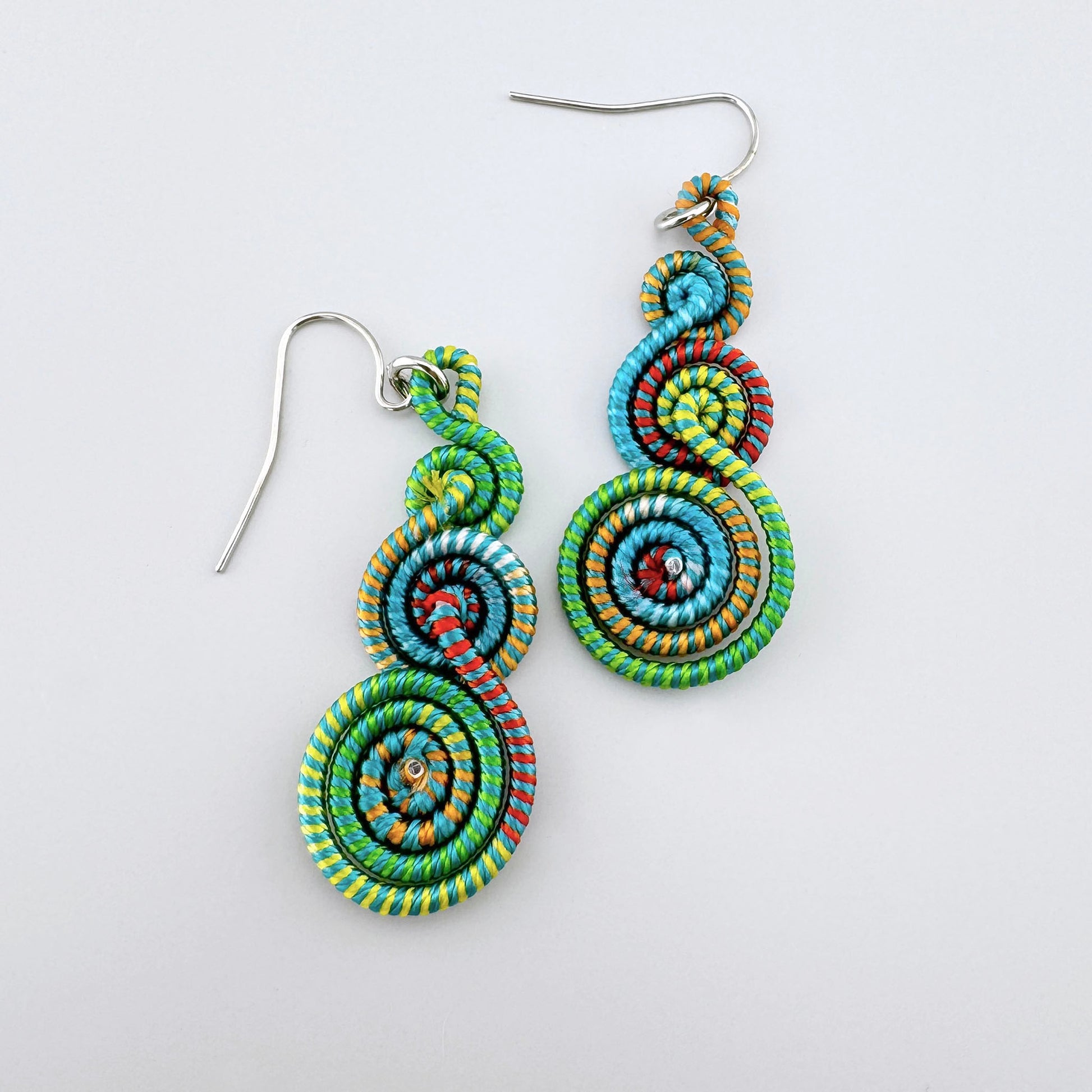 Colorful spiral earrings made from multicolored threads with a three-tier design.