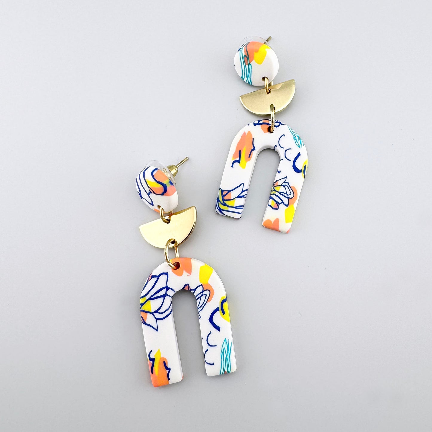 Colorful earrings with a printed design and gold semicircular accents.