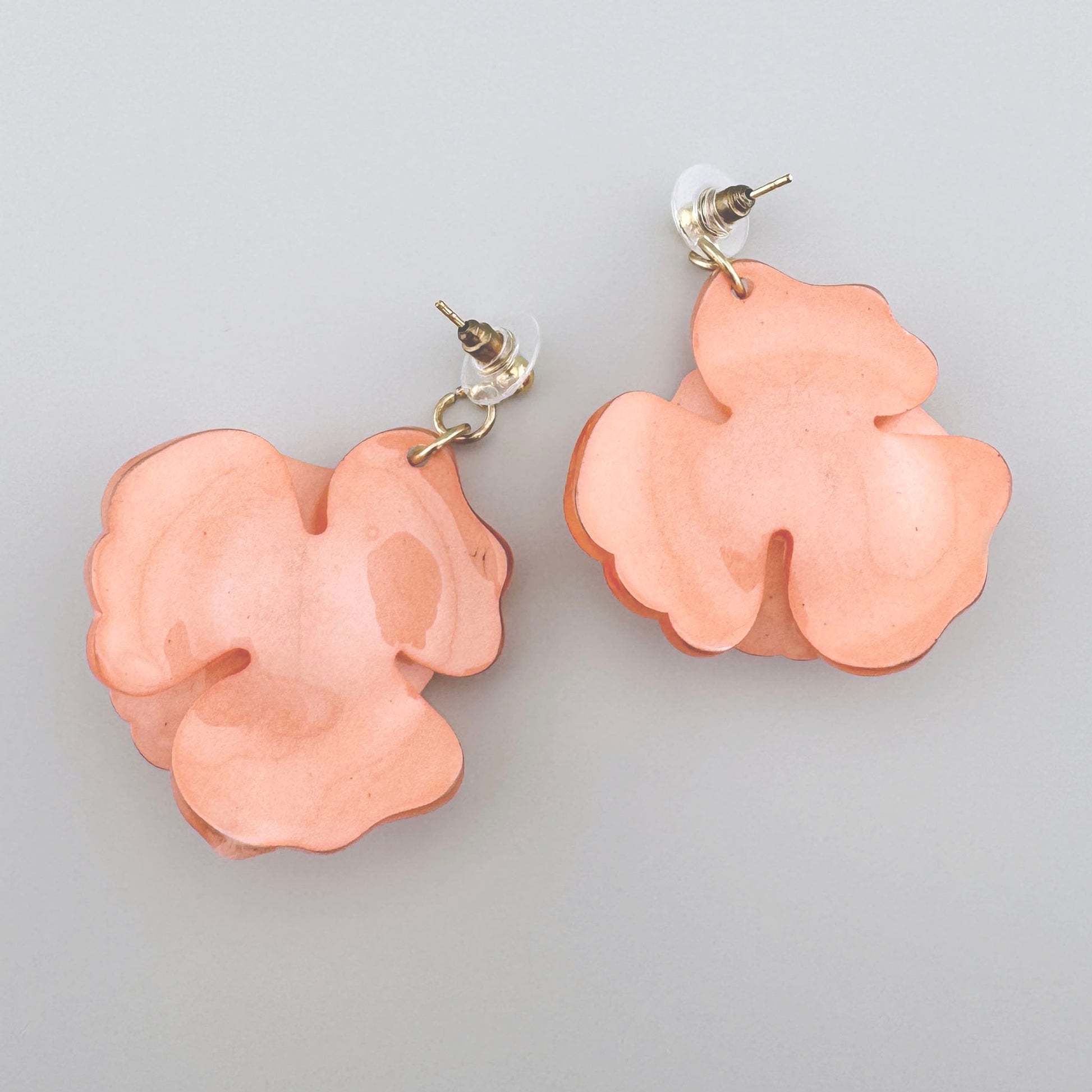 Pink rose-shaped earrings made from translucent material with gold accents.