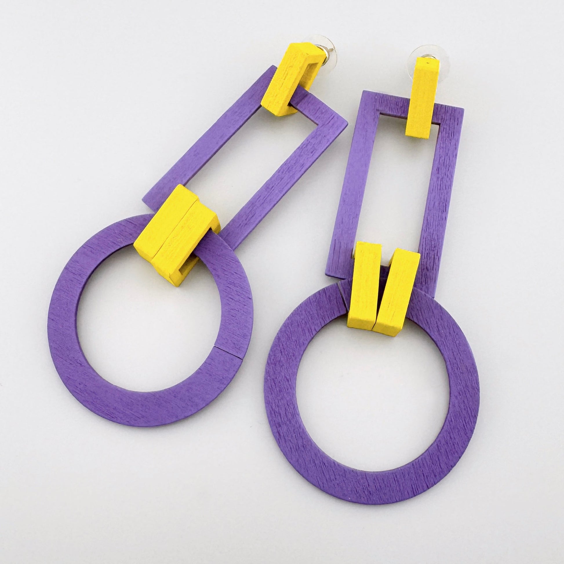 Geometric earrings with purple circles and yellow rectangular accents.