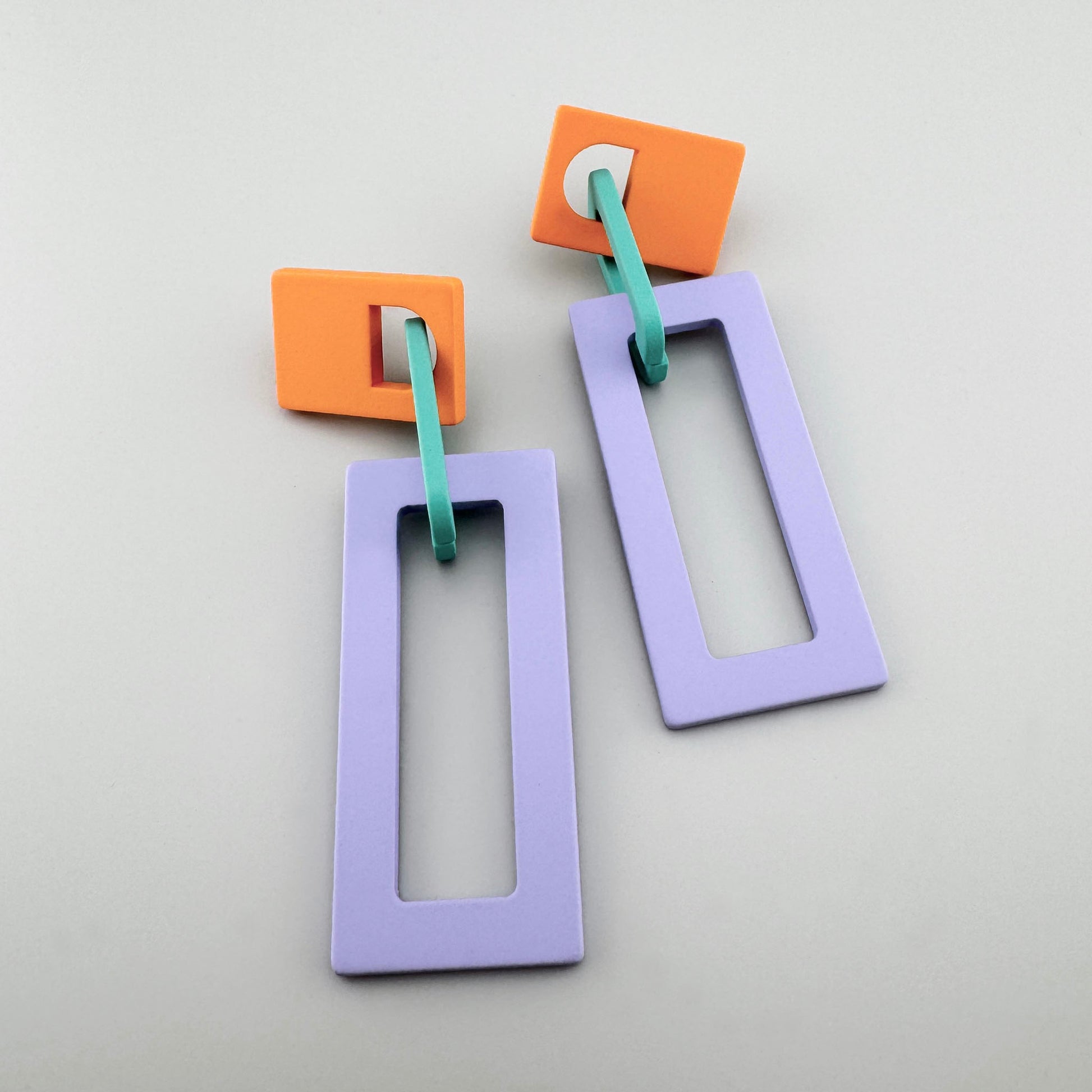 Bold geometric earrings with orange, blue, and purple rectangular shapes.