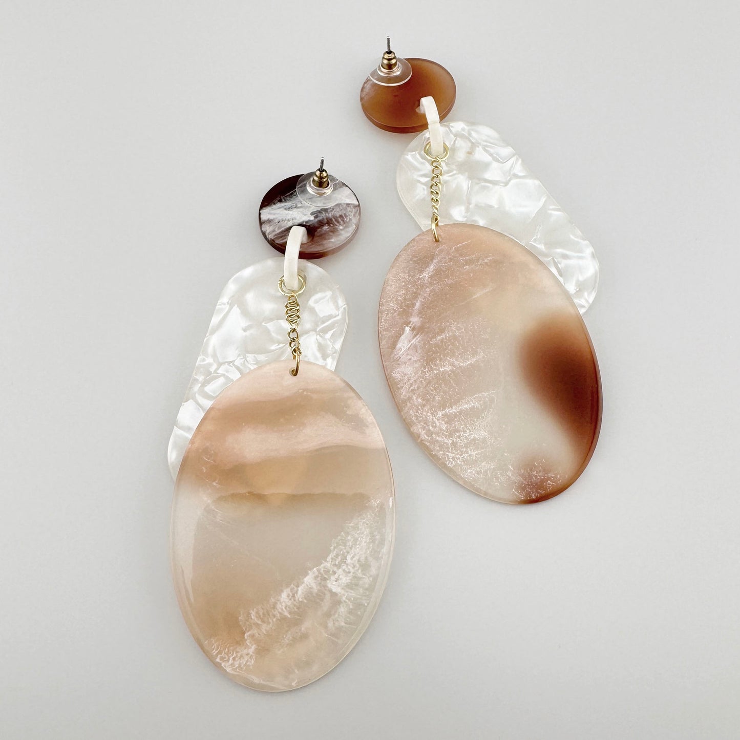 Earrings with large oval pendants in soft brown and pearlescent shades.