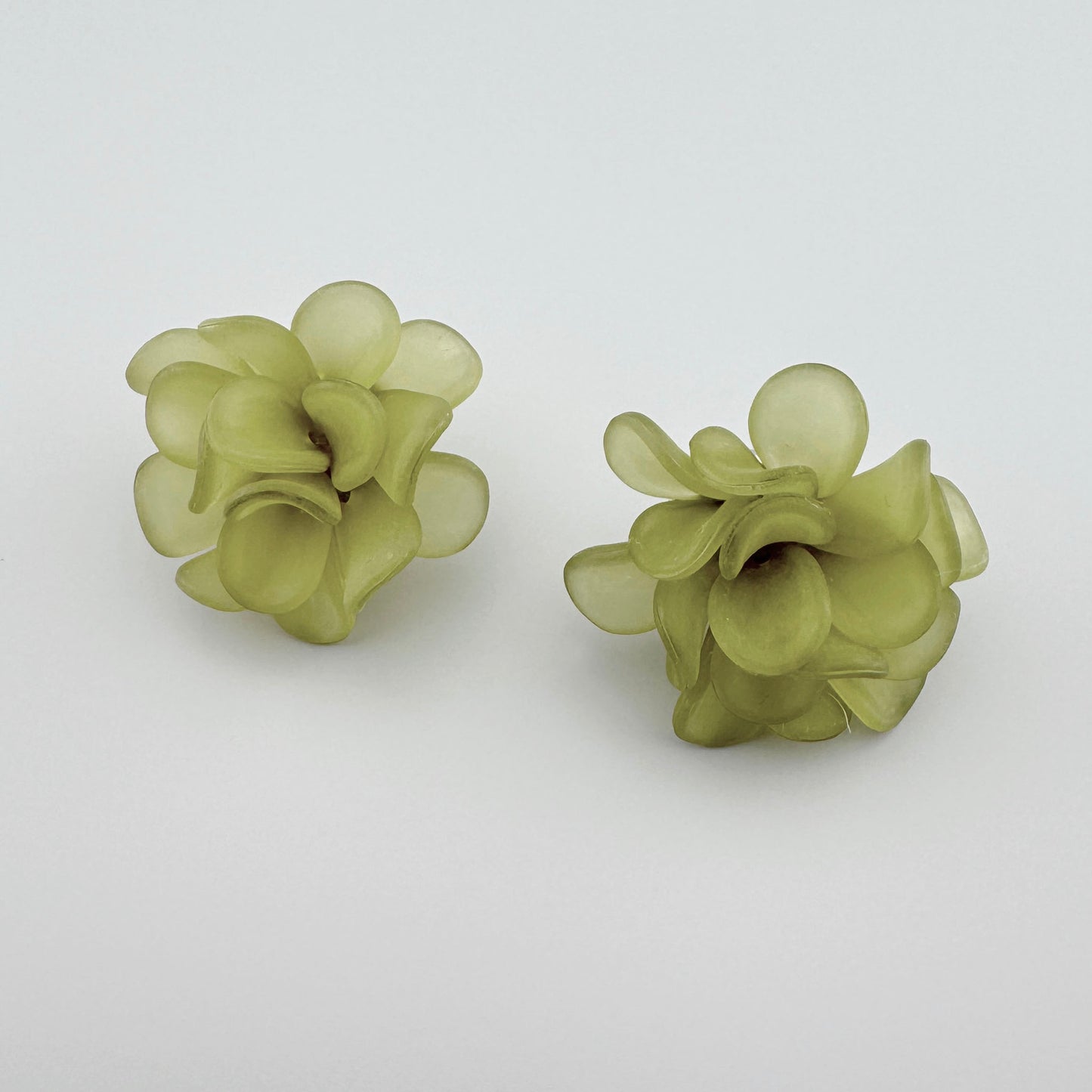 Light green earrings shaped like delicate flowers.