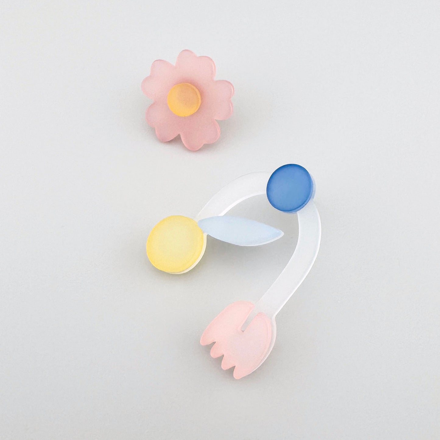 Flower-shaped earrings with pastel yellow, blue, and pink elements.