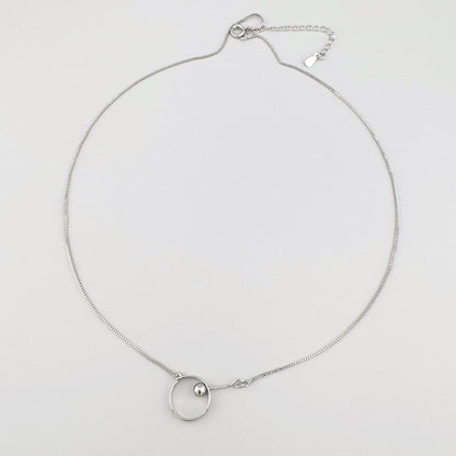 Minimalist necklace with a silver-plated pendant featuring a circle and a small sphere.