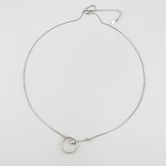 Minimalist necklace with a silver-plated pendant featuring a circle and a small sphere.