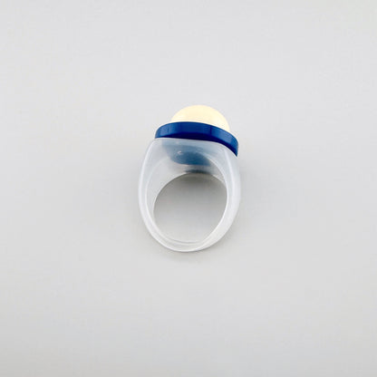 Bague en plastique transparent avec sphère crème et accent bleu marine.