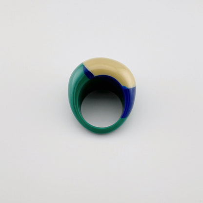 Auffälliger Ring in Beige-, Grün- und Blautönen aus glänzendem Kunststoff.