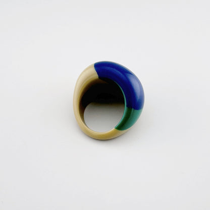 Asymmetrischer Ring, der Beige, Grün und tiefes Blau kombiniert.