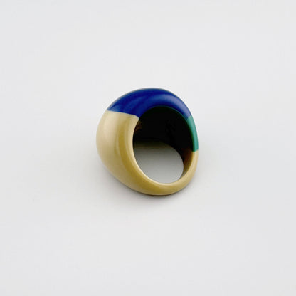 Anillo asimétrico que combina beige, verde y azul profundo.