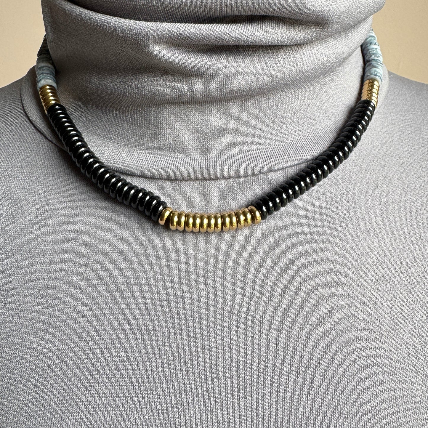 Necklace with gray and black ceramic discs and shiny gold details, French brand Ikita.