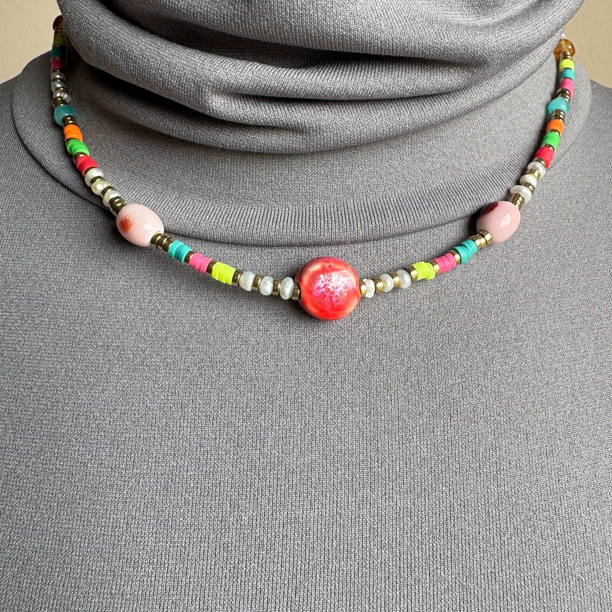 Colorful beaded necklace with a glossy red ceramic centerpiece, French brand Ikita.