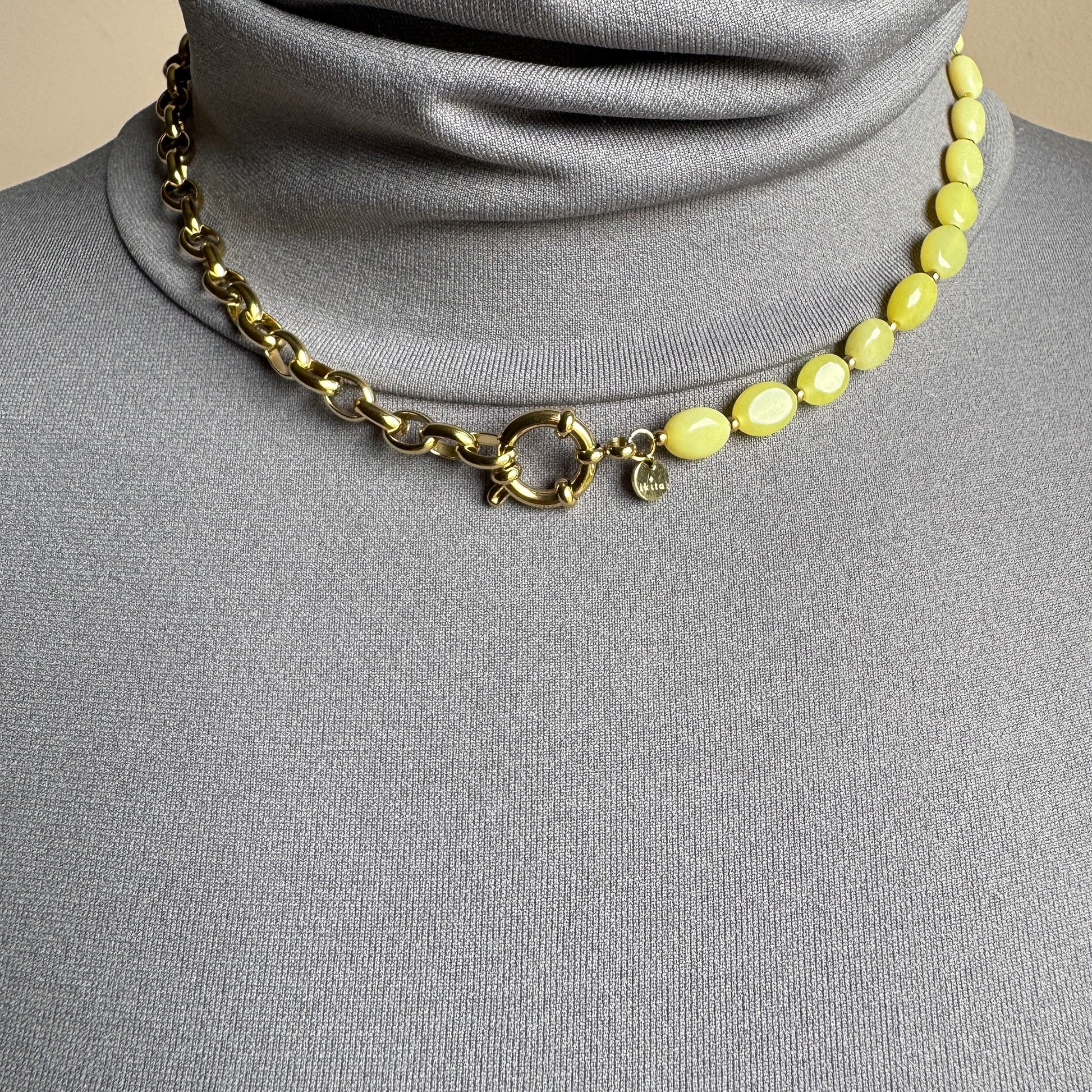 Asymmetric necklace with lemon-yellow jade stones and gold chain, French brand Ikita.