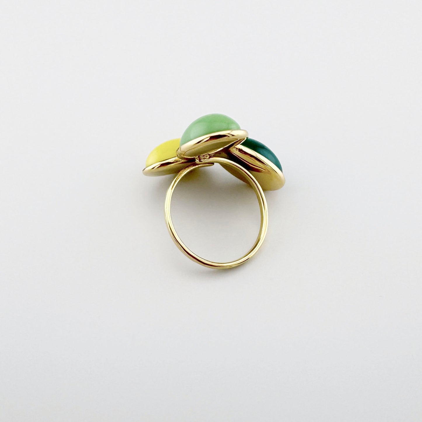 Anillo dorado con tres elementos de colores en tonos amarillo, verde y verde oscuro.