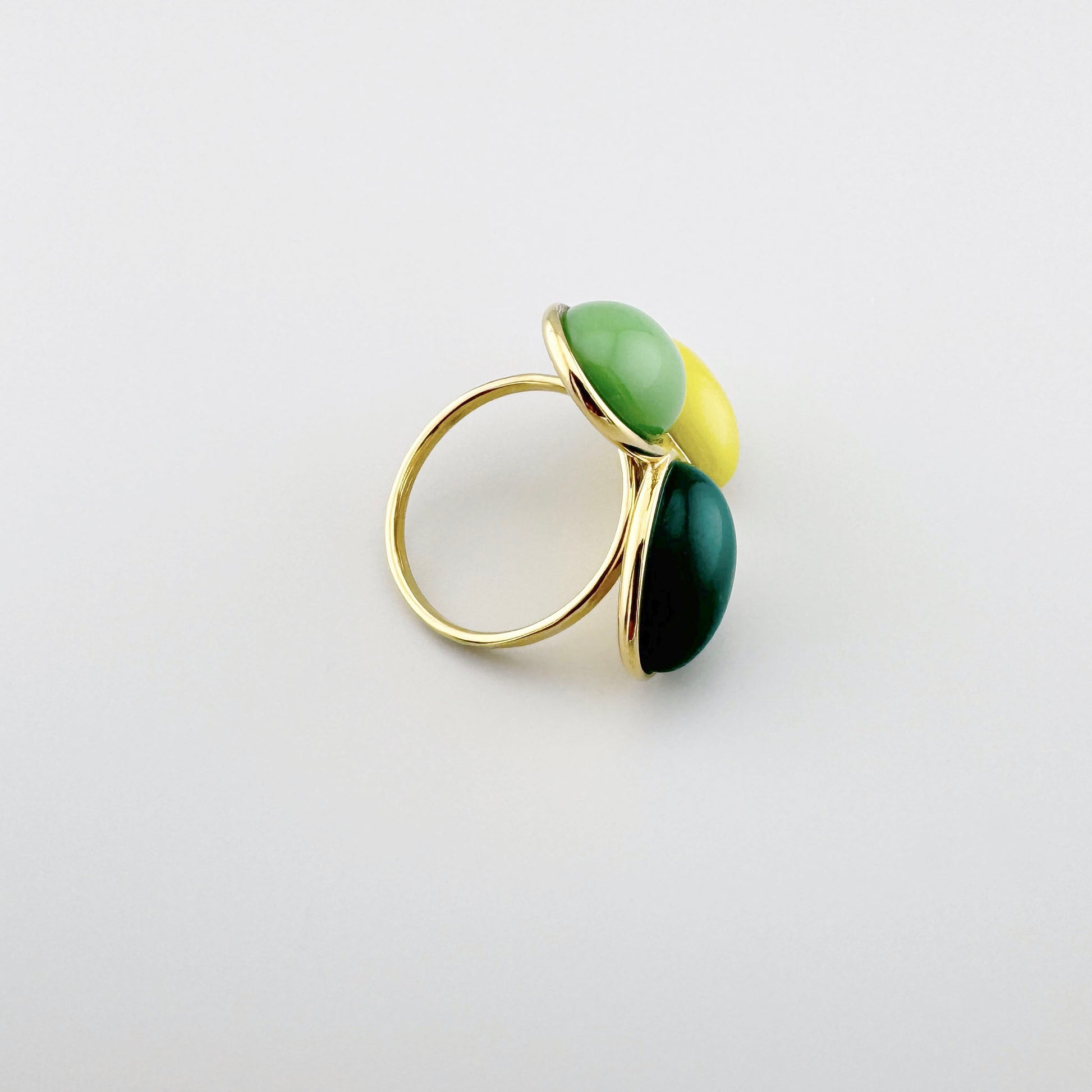 Bague dorée avec trois éléments colorés en jaune, vert et vert foncé.