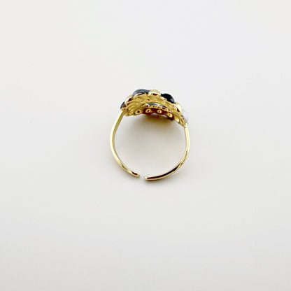 Bague dorée avec des détails en émail noir et gris, au design moderne.