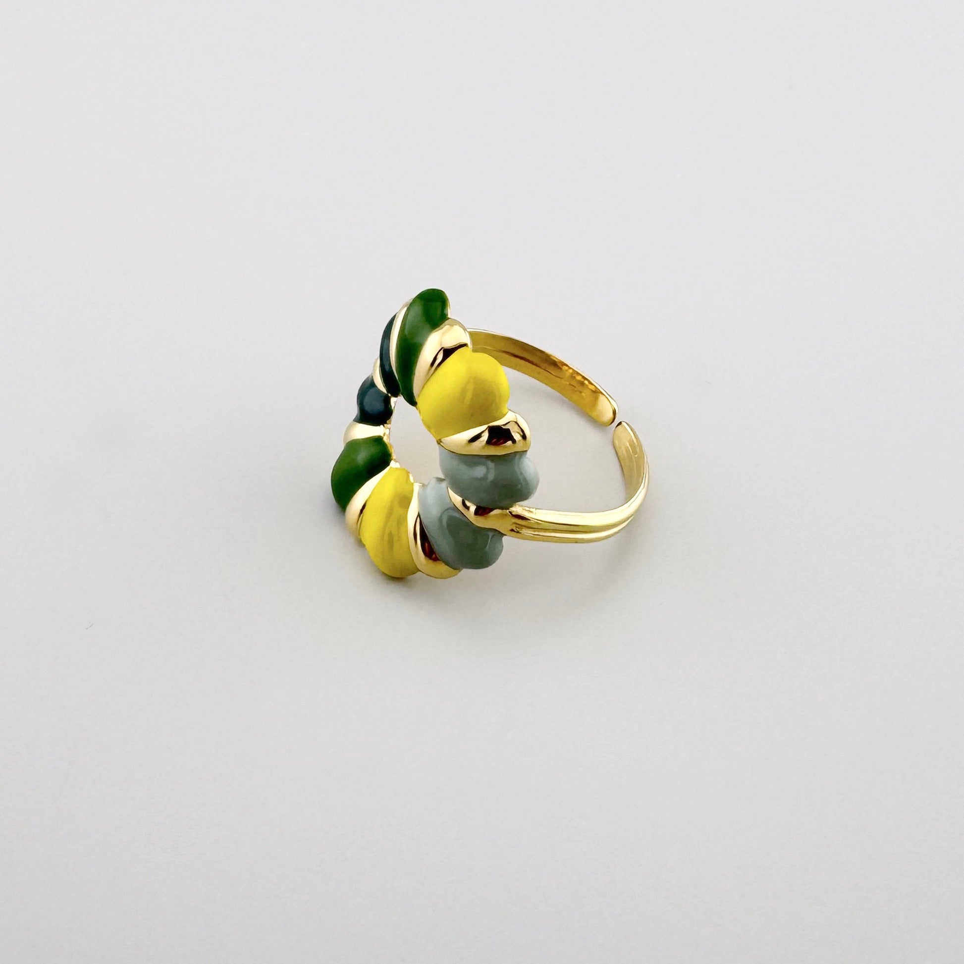 Gold-colored ring with colorful enamel details in shades of green, yellow, and gray.