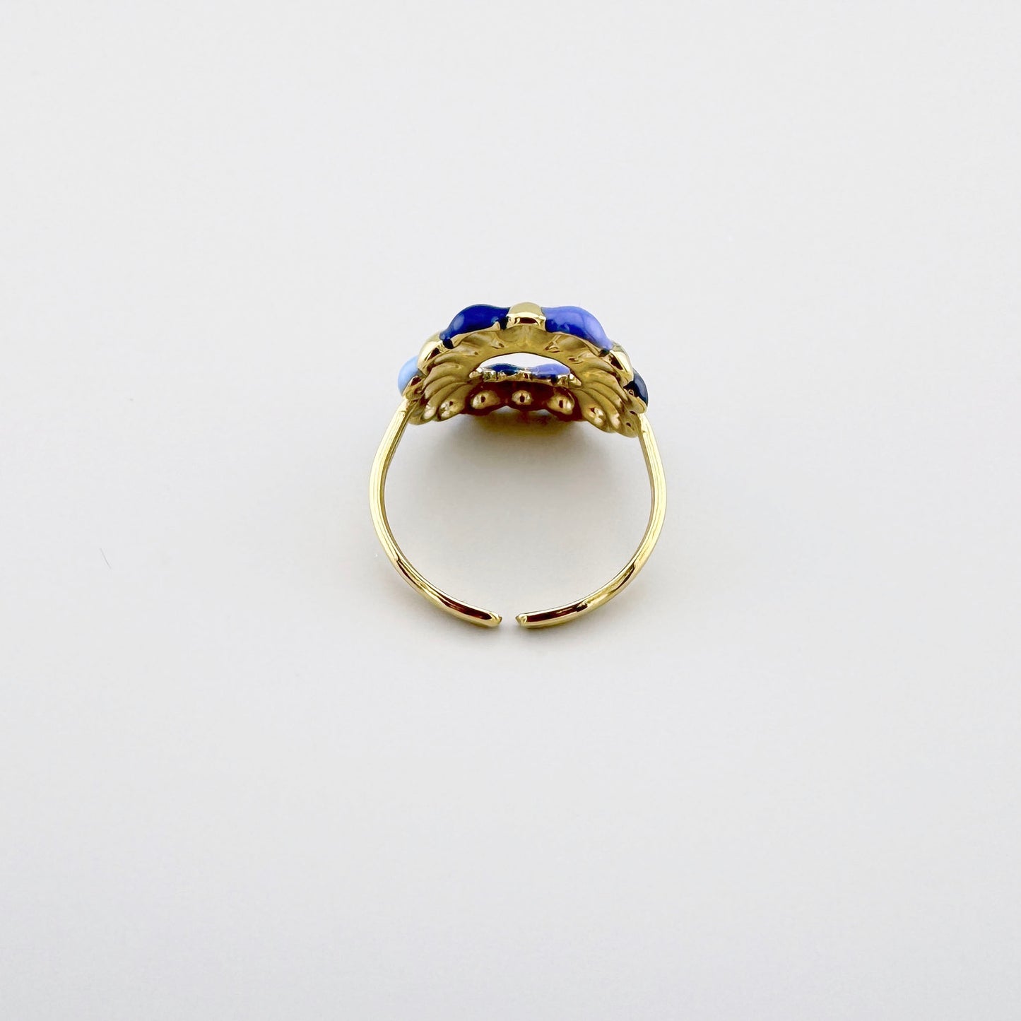 Anillo dorado con detalles de esmalte en varios tonos de azul.