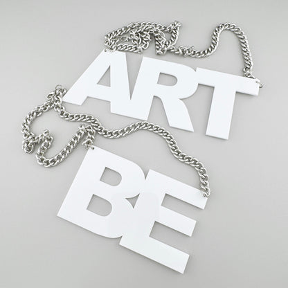 Set of two necklaces with white pendants “ART” and “BE” on chunky chains.