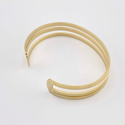 Pulsera abierta de acero dorado con tres finas bandas, marca francesa Ikita.