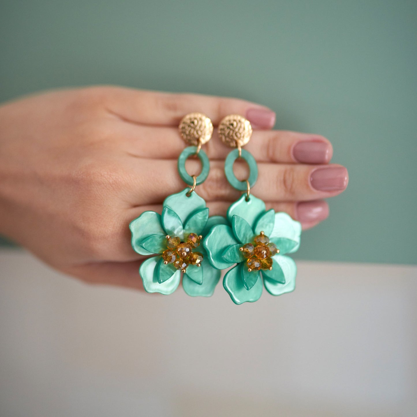 Green flower-shaped earrings with gold accents and crystals.