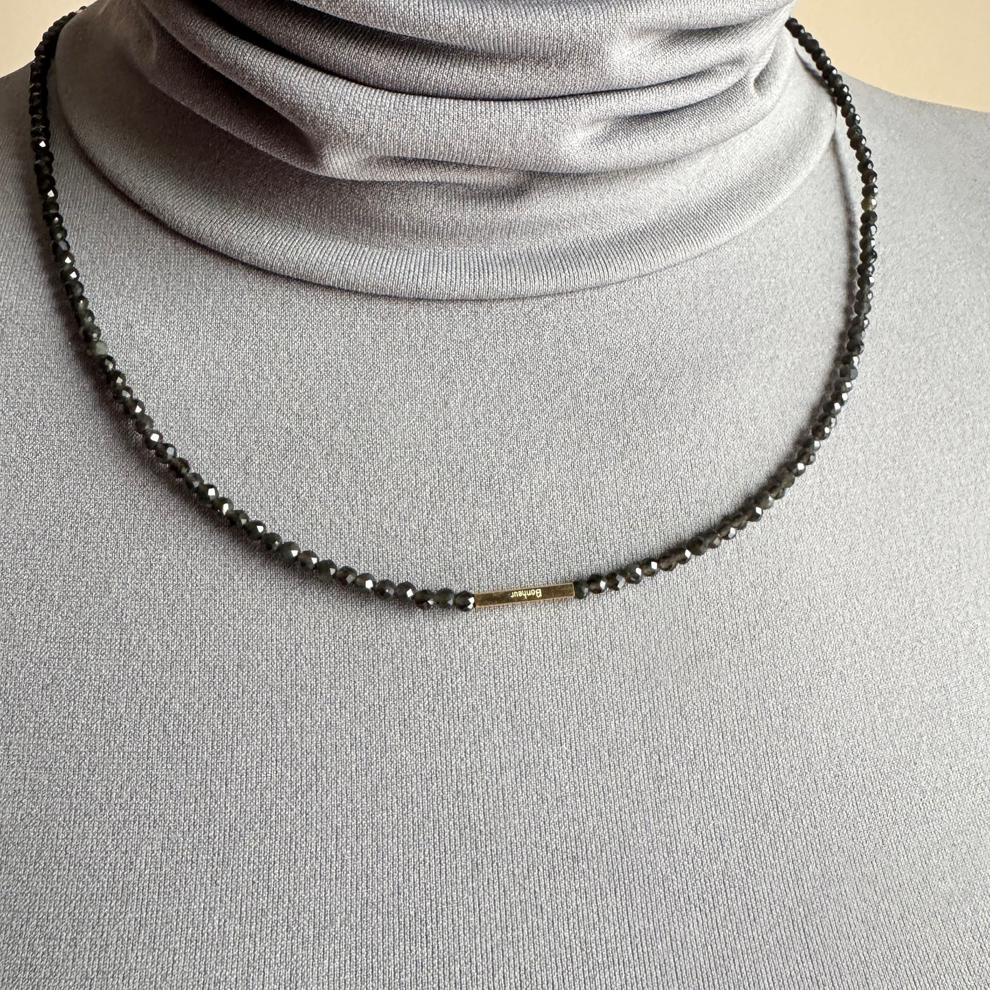 Agate necklace IRL worn close to the neck with dark faceted beads and gold accents