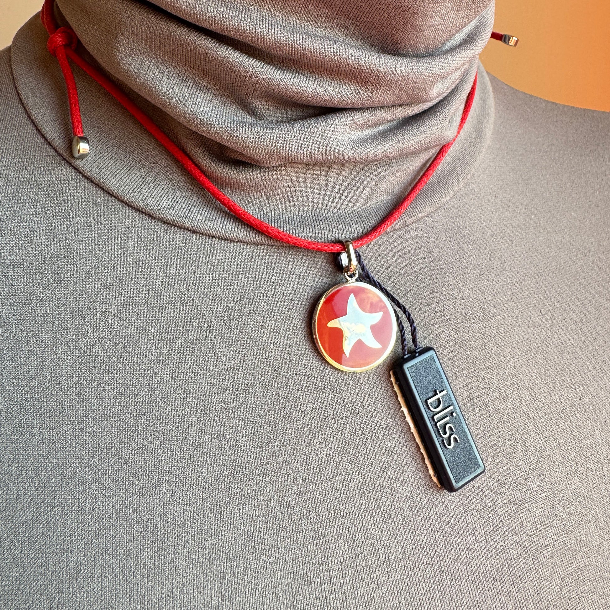 Red‑enamel anchor pendant on adjustable cord, subtle steel shine