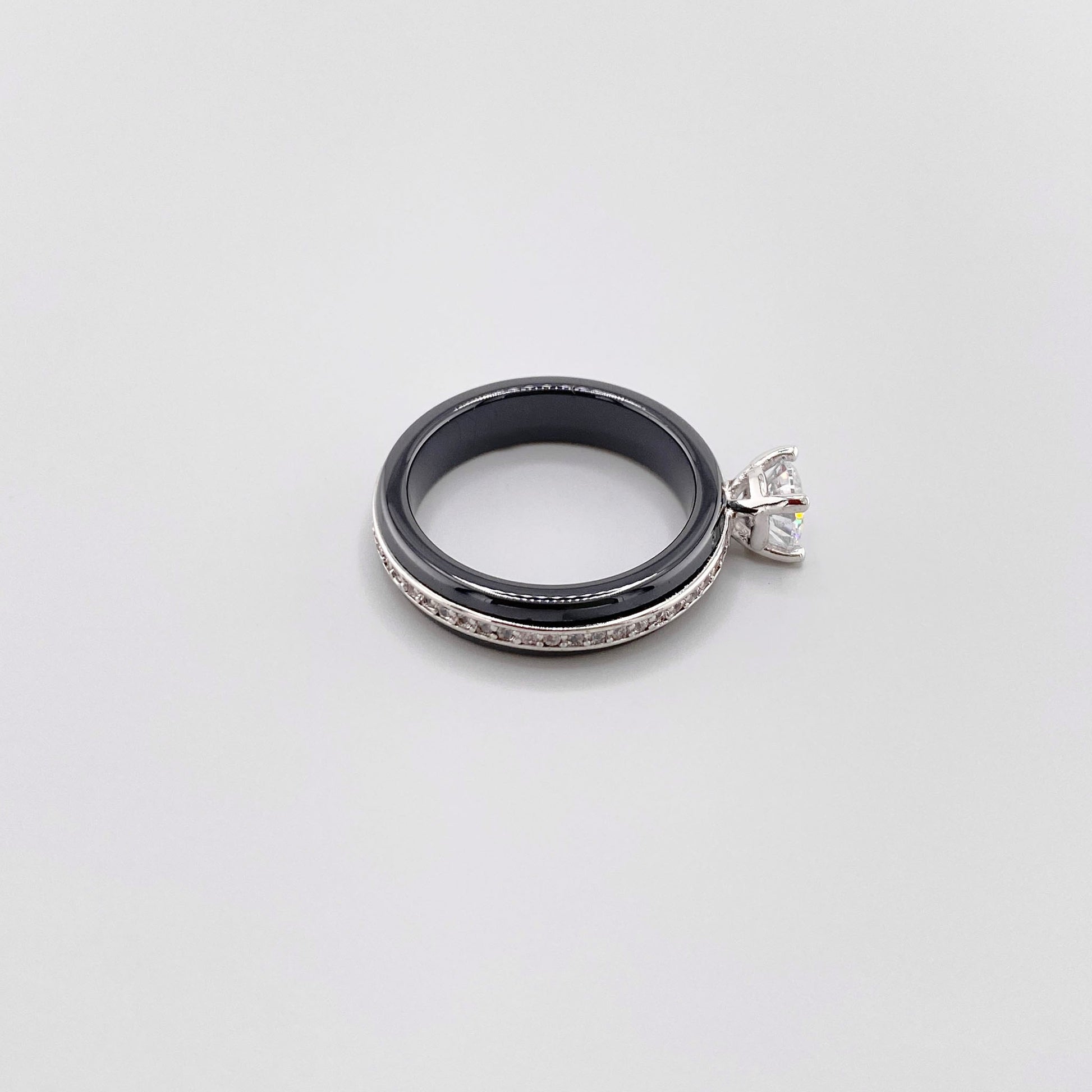 Black ceramic ring by Luxury Avenue shown at an angle with a round crystal and silver-tone edge