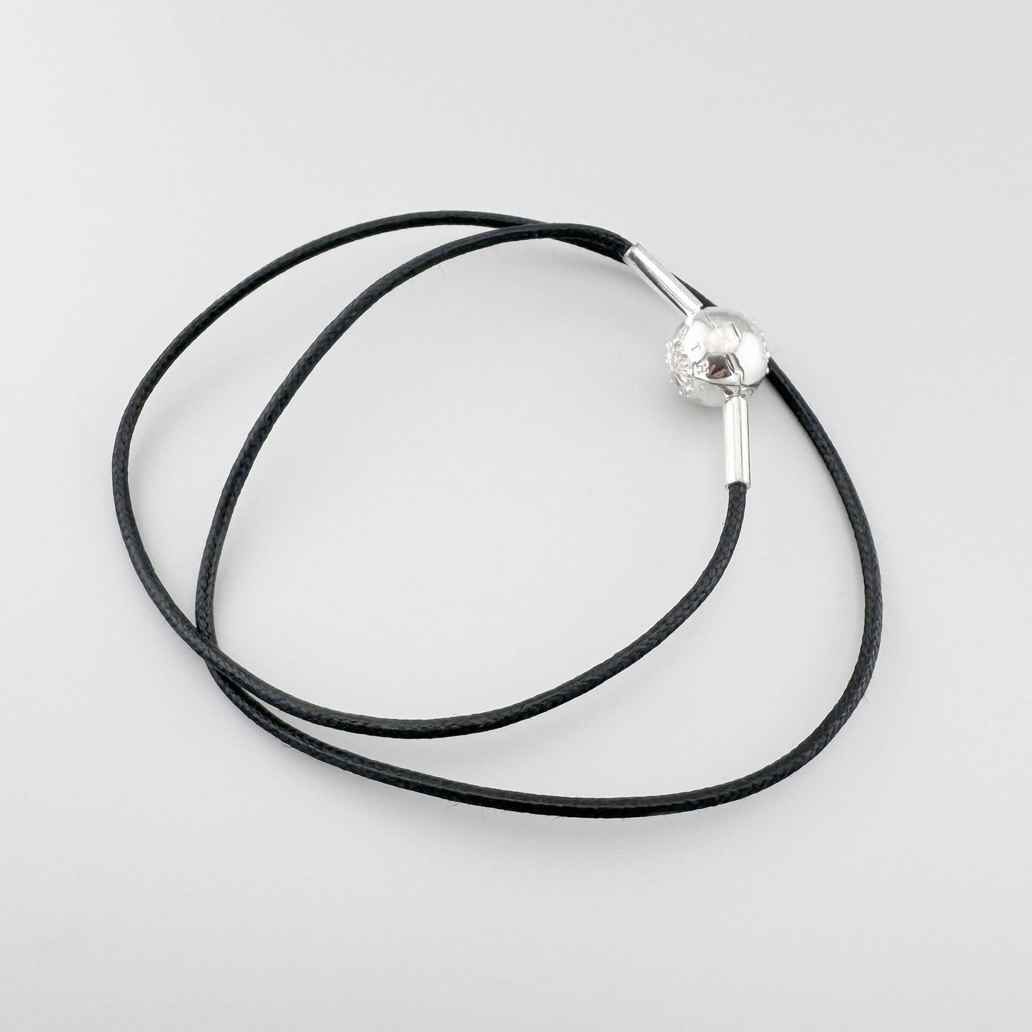 Czarny choker Thomas Sabo z dekoracyjną srebrną kulką i metalowymi końcówkami na jasnym tle