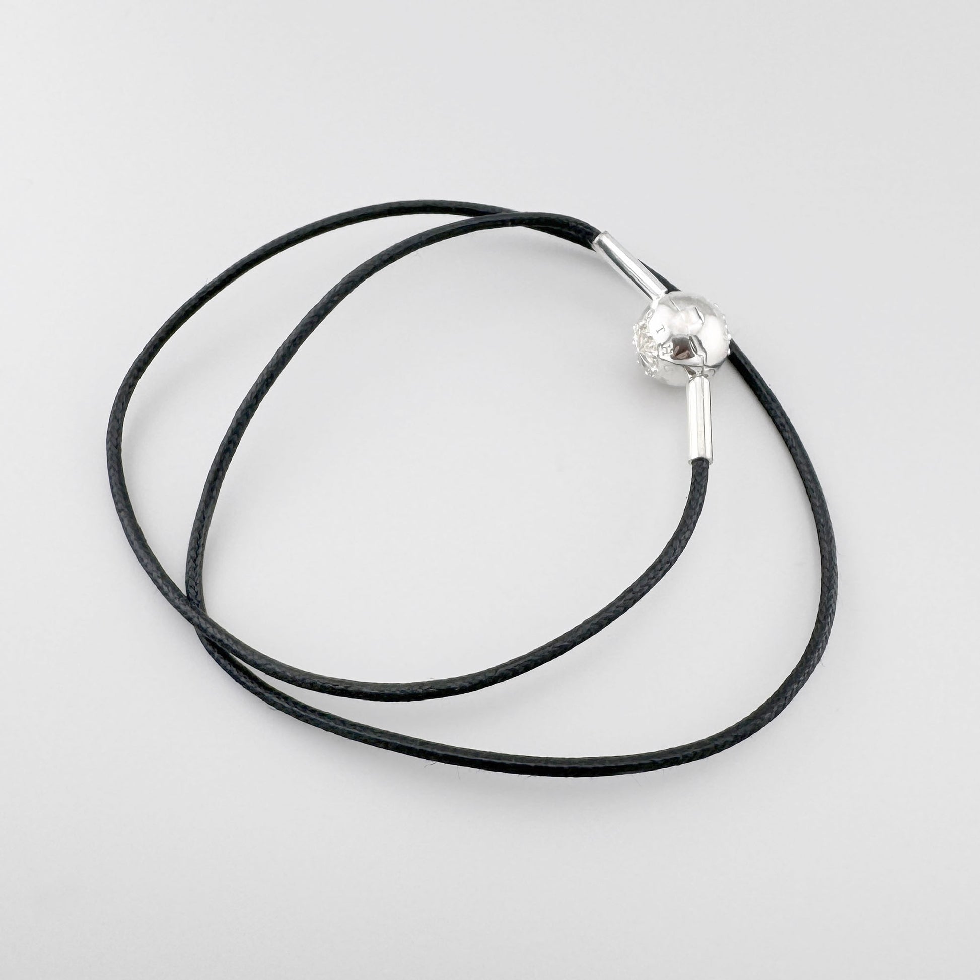 Czarny choker Thomas Sabo z dekoracyjną srebrną kulką i metalowymi końcówkami na jasnym tle