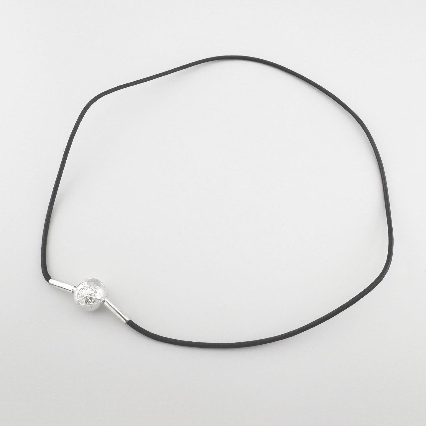 Schwarzer Choker von Thomas Sabo mit silberner Kompasskugel flach auf hellem Hintergrund