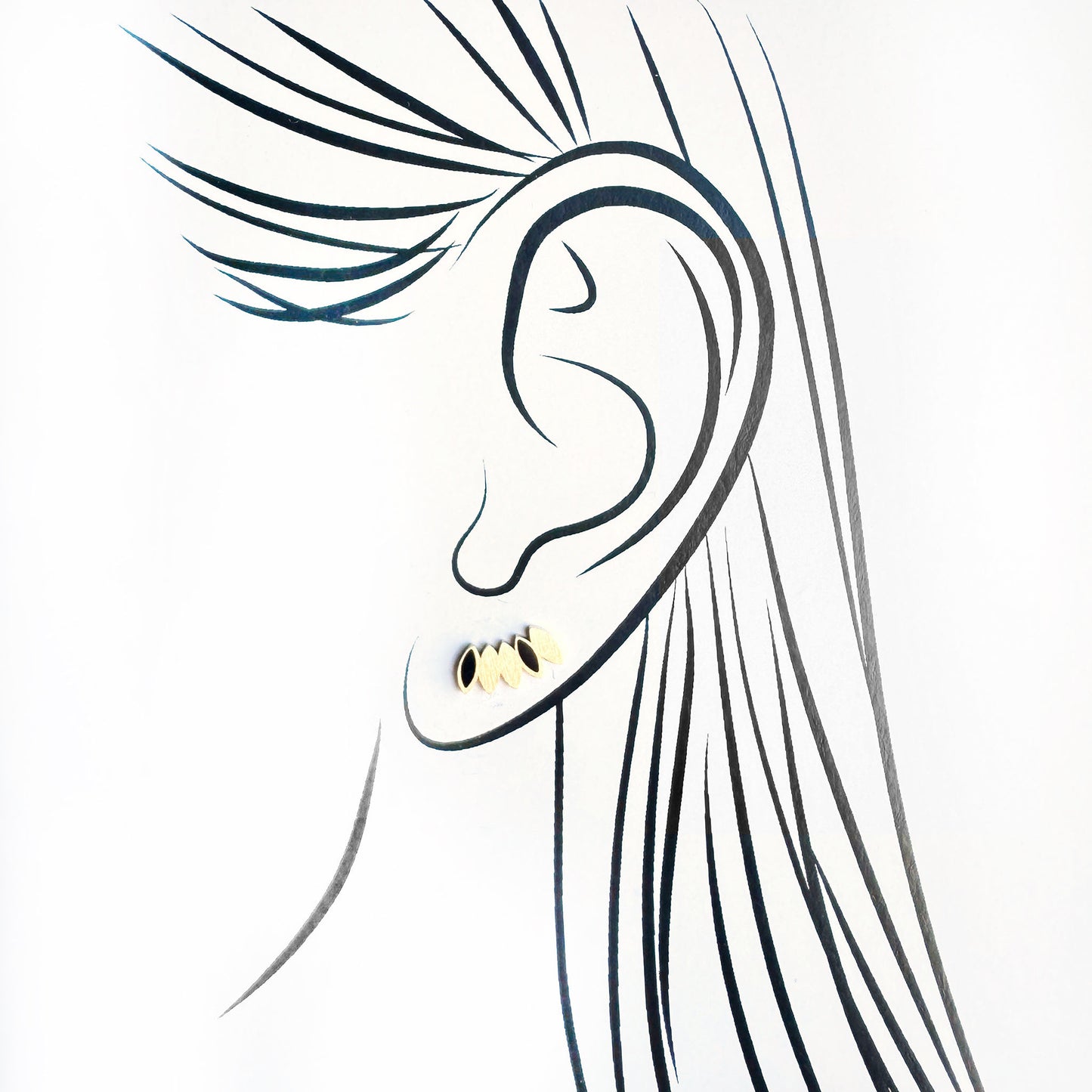 Small black enamel earrings with gold matte base worn close to the ear