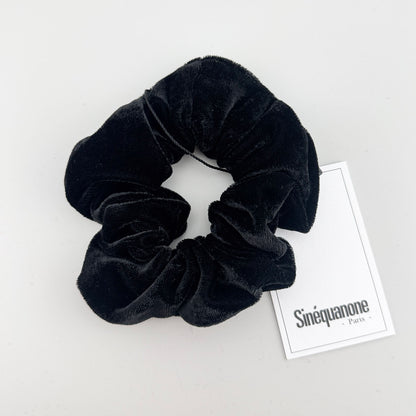 Black velvet scrunchie by Sinequanone Paris displayed beside its branded tag