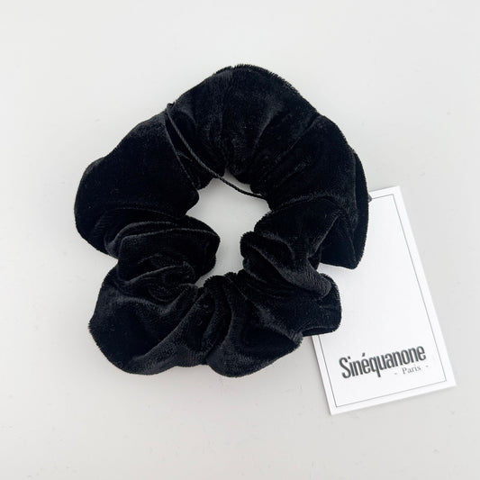Black velvet scrunchie by Sinequanone Paris displayed beside its branded tag