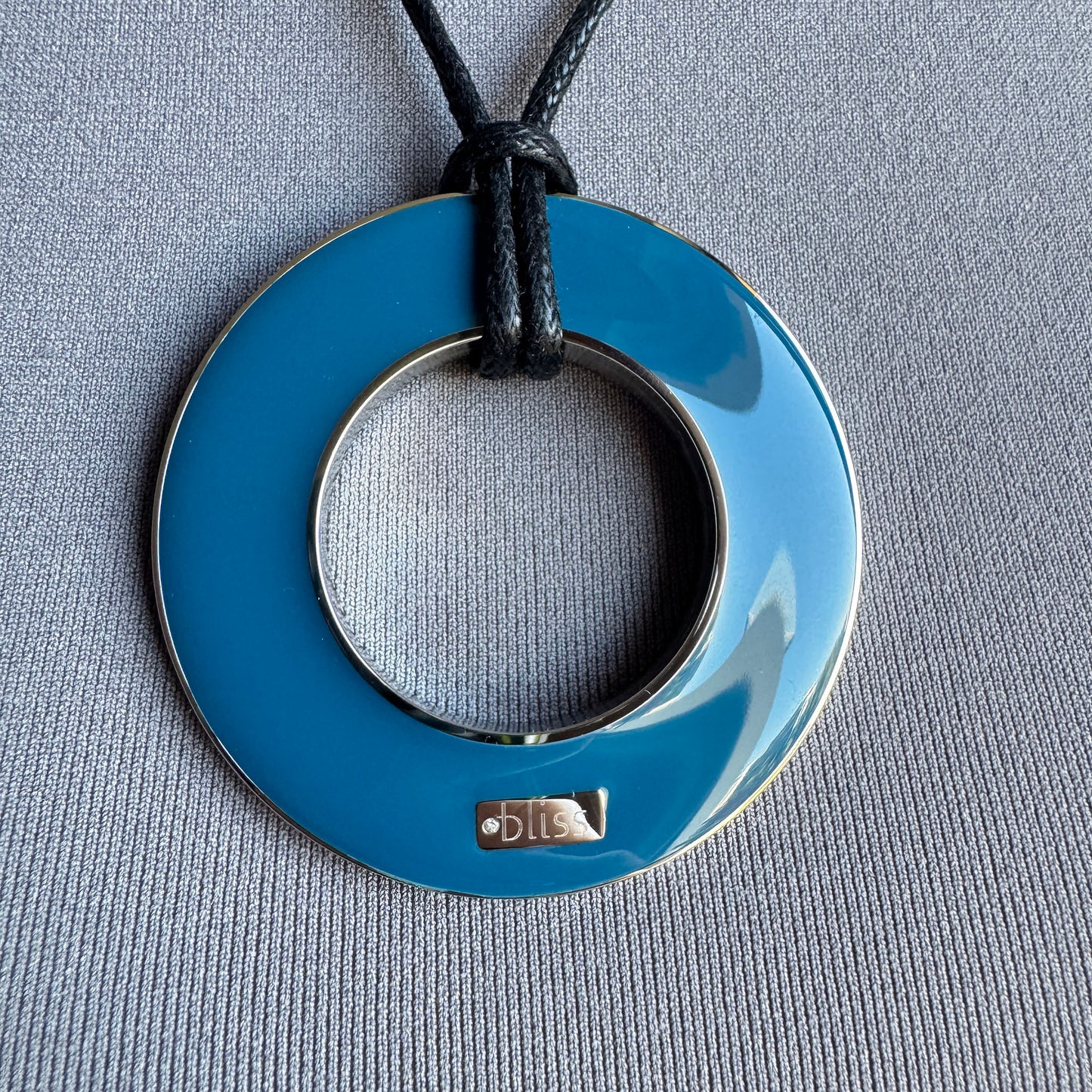 Collar reversible con esmalte azul en primer plano sobre cordón negro