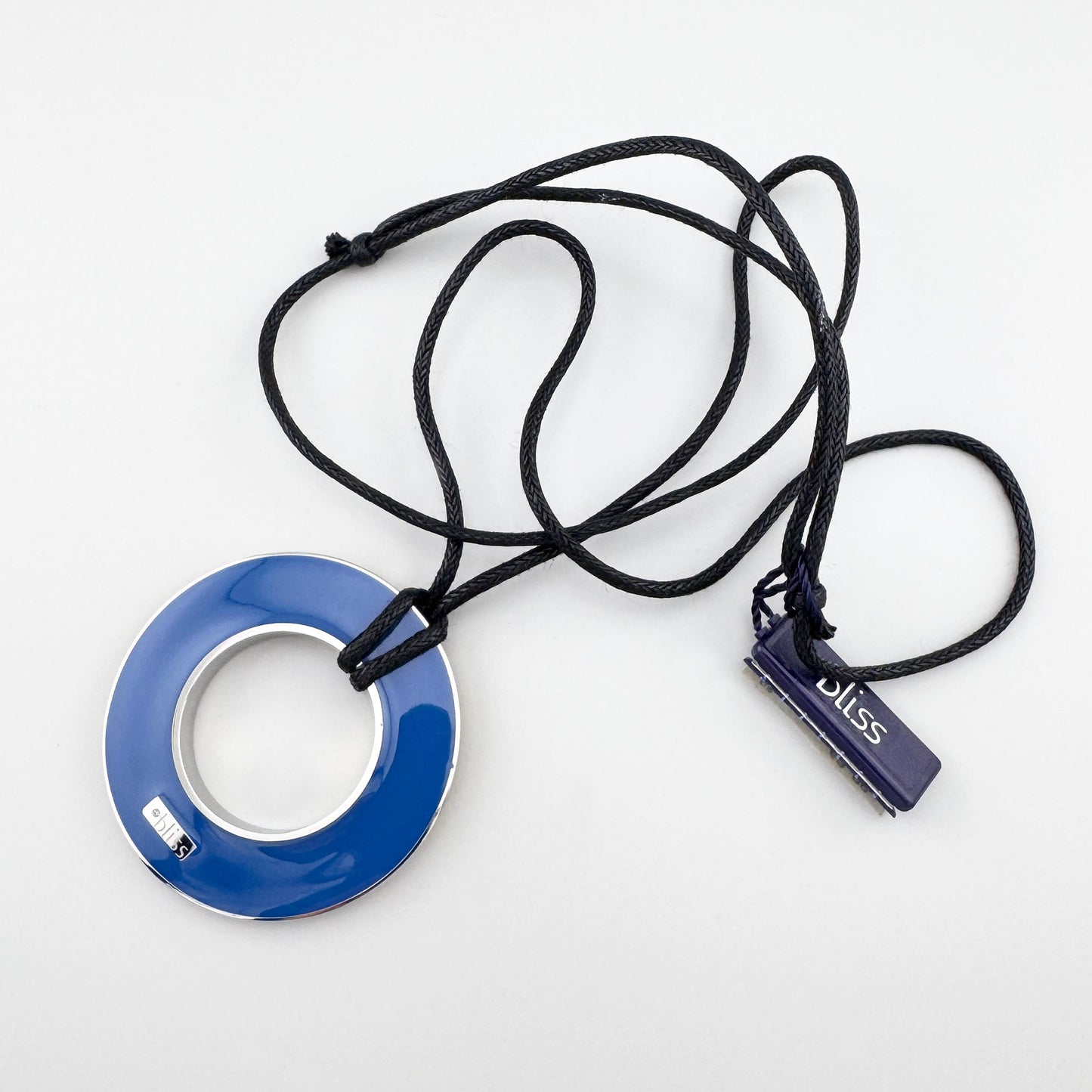 Collier réversible en émail bleu posé à plat sur fond clair