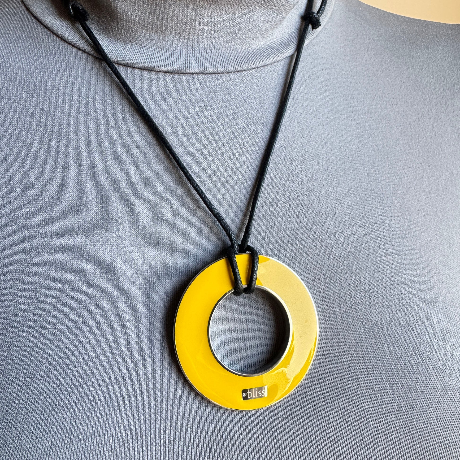 Reversible enamel necklace worn on black cord with yellow pendant