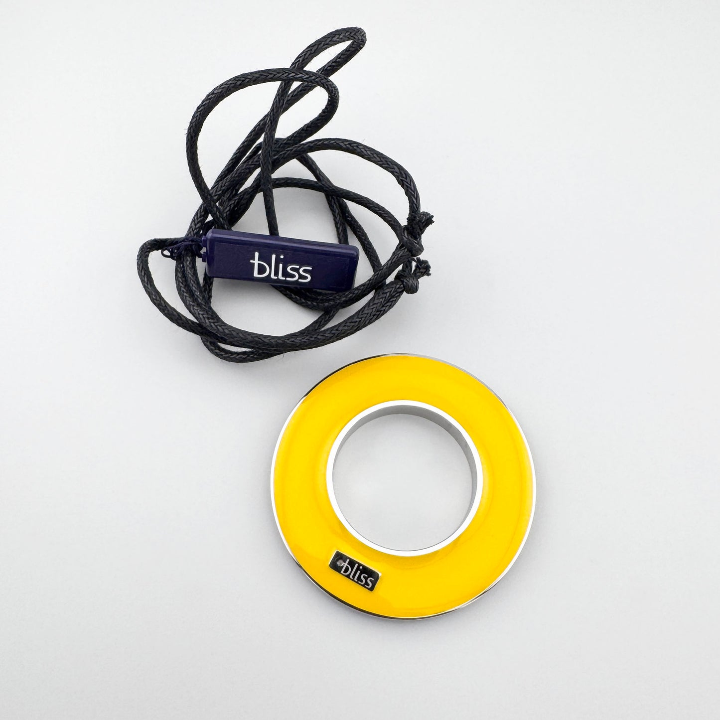 Naszyjnik dwustronny z emalią w żółtym kolorze ułożony na jasnym tle