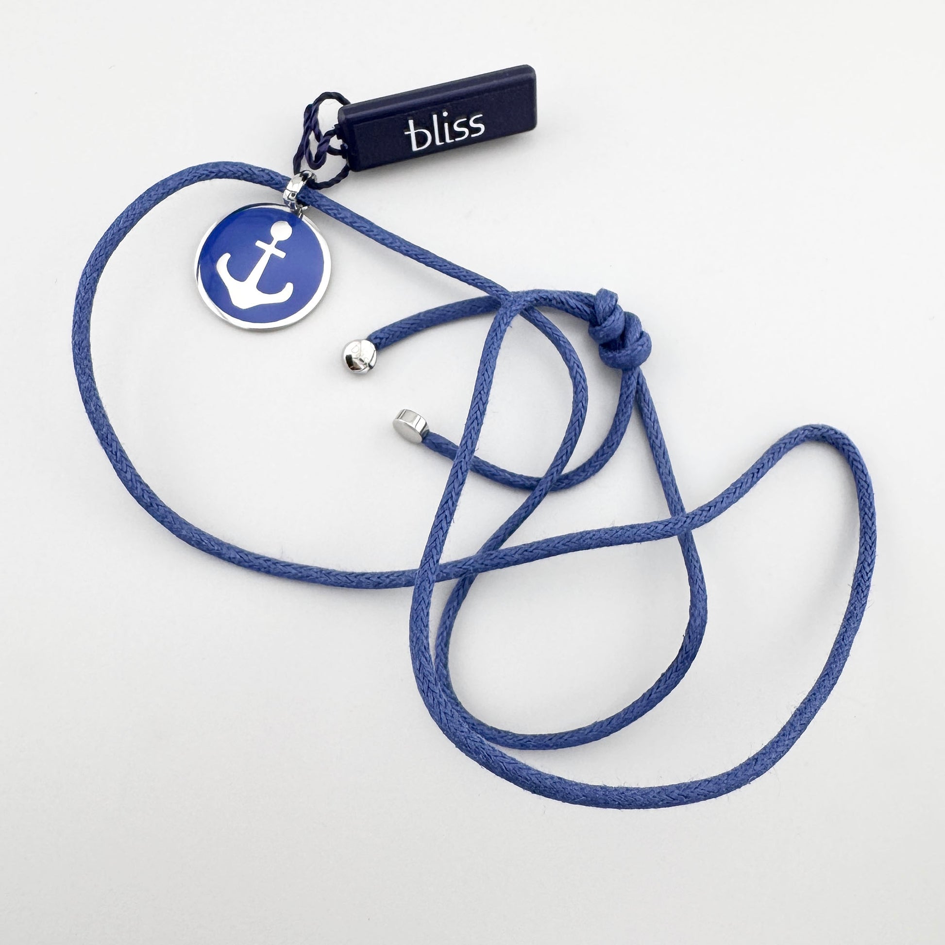 Collier avec ancre en émail bleu posé à plat sur fond clair