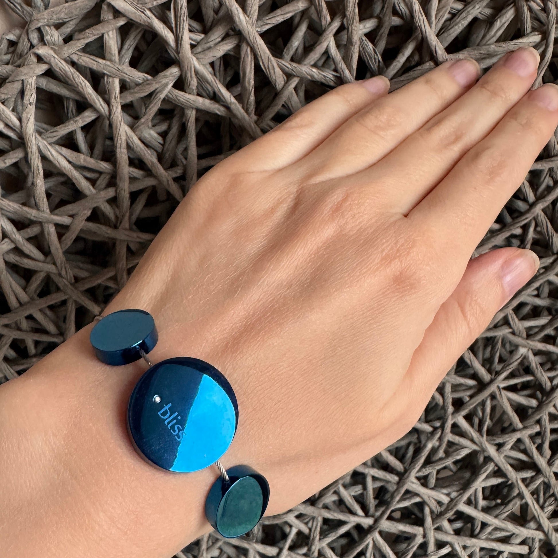 Blue disc bracelet worn on the wrist with a sleek, minimalist shine