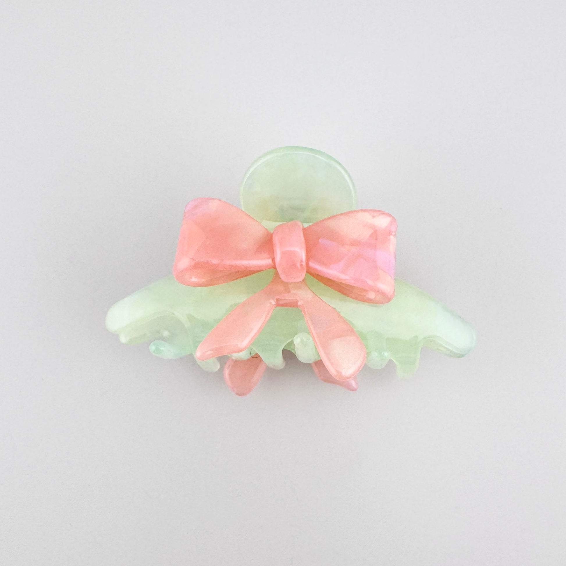 Pastel bow hair claw with soft pink and mint tones in a glossy finish
