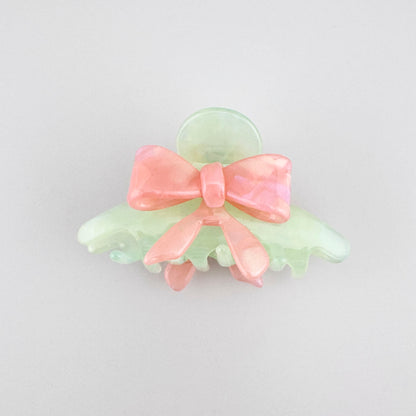 Pastel bow hair claw with soft pink and mint tones in a glossy finish