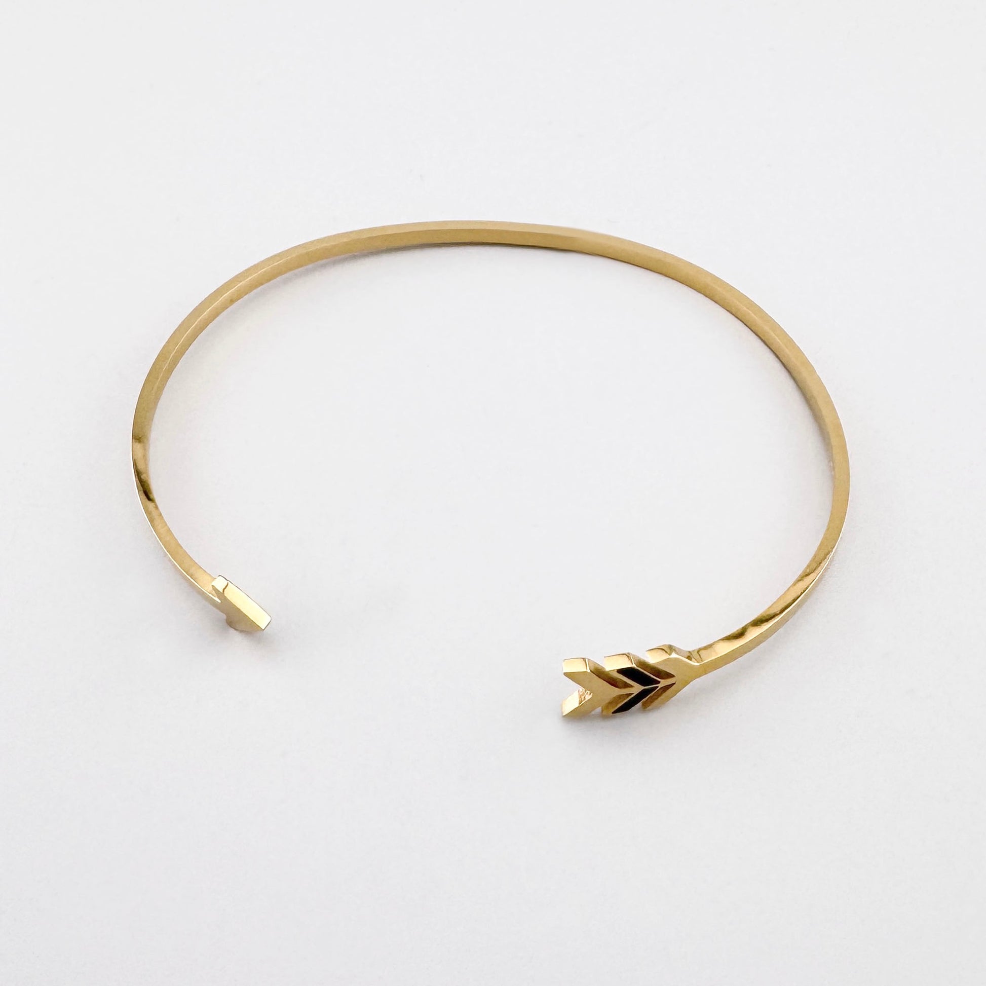 Goldfarbene Armspange mit Pfeilmotiv als dezenter Ausdruck von Richtung und Stil