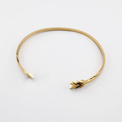 Goldfarbene Armspange mit Pfeilmotiv als dezenter Ausdruck von Richtung und Stil